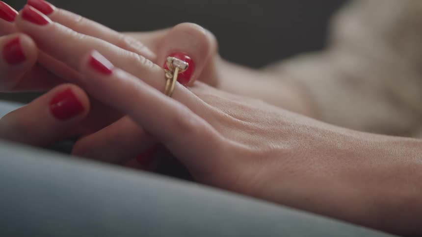 A woman looks at a diamond ring on a her hand