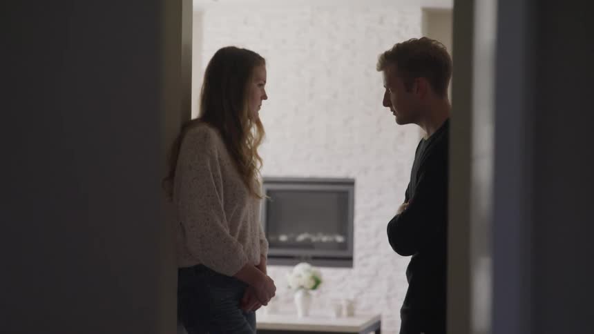 A man and a woman standing by a doorway with a table in the background