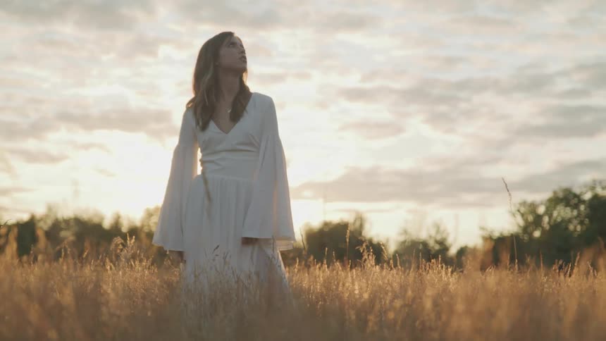 A woman is standing outdoors at dusk