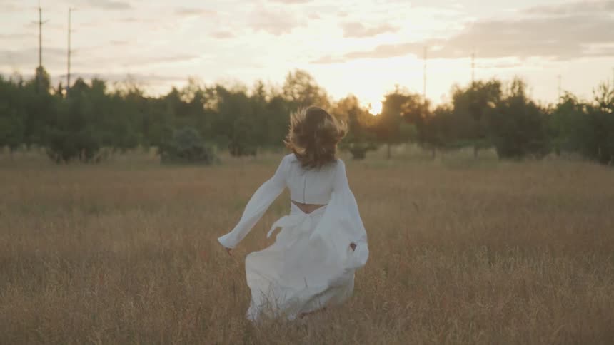 A woman is dancing outdoors at dusk