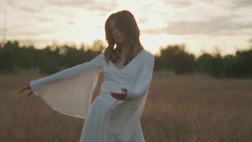 A woman is dancing outdoors at dusk