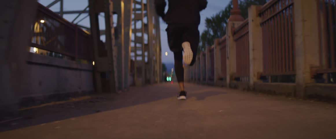 A man is jogging outdoors at dusk