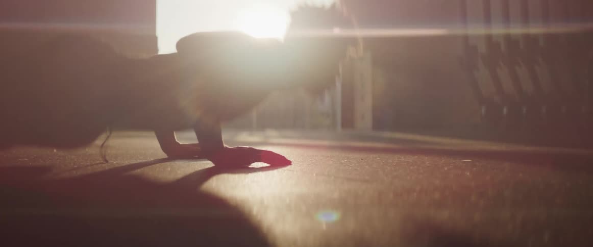 Black man doing push ups is silhouetted against sunset