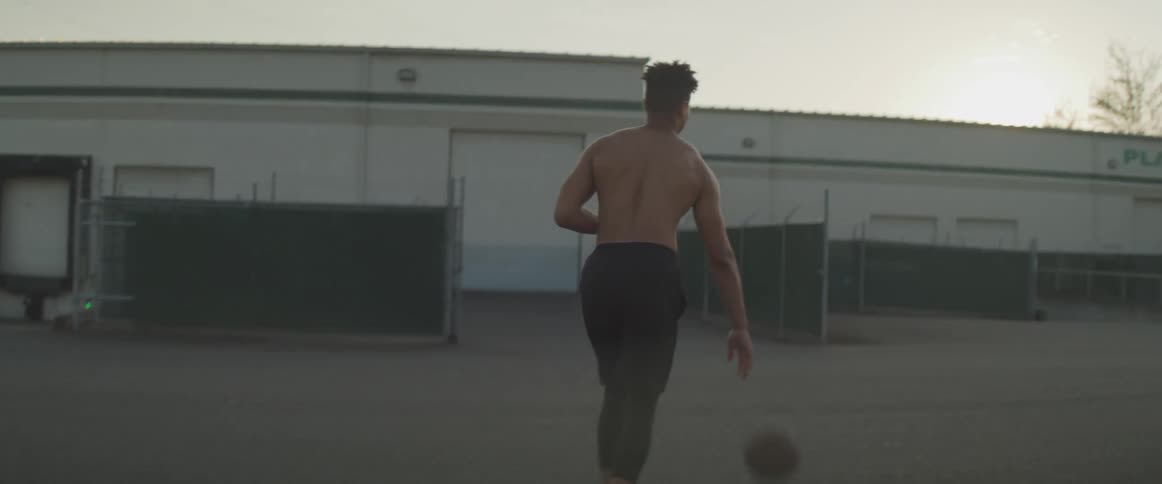 A teenage boy dribbles a basketball outside