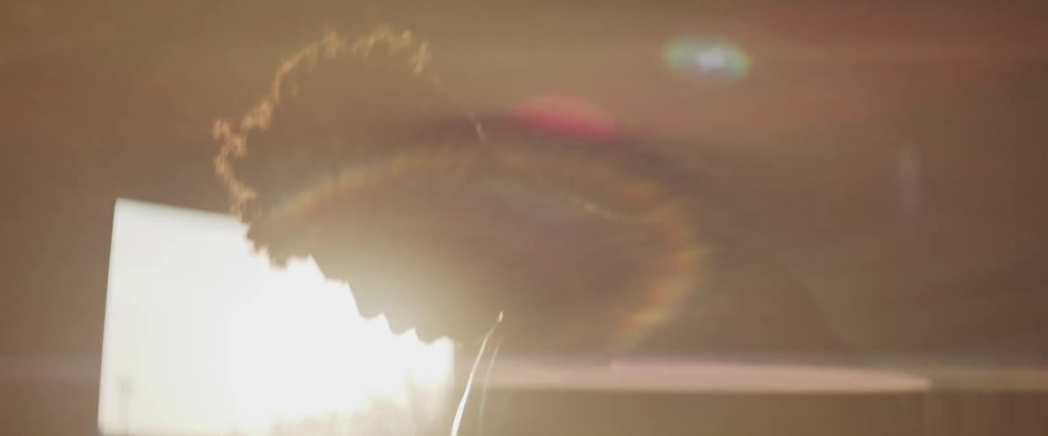The silhouette of a shirtless muscled man with sunlight glaring through an open doorway