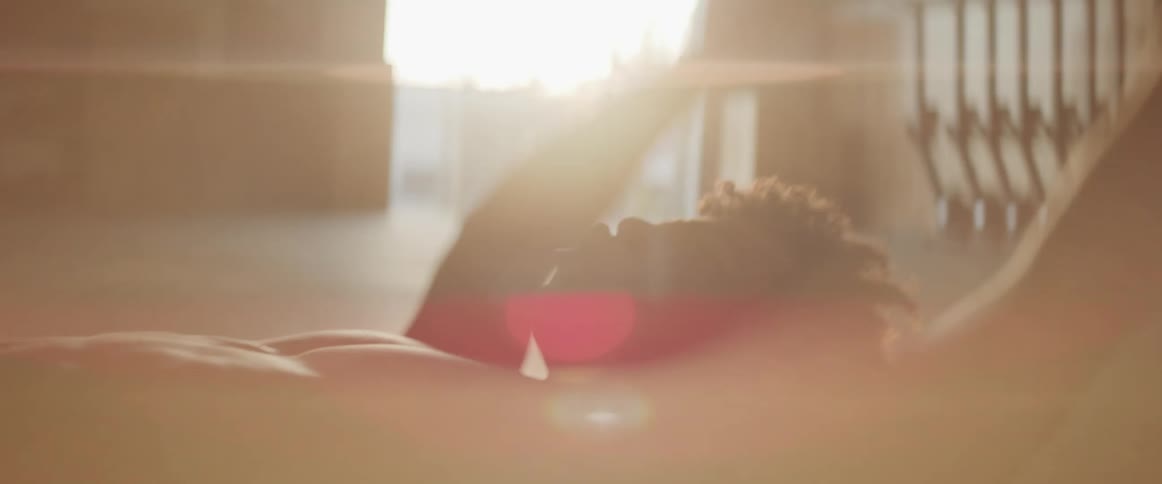 Young muscular man exercises on the floor of a gym while sunset sunlight filters through city buildings