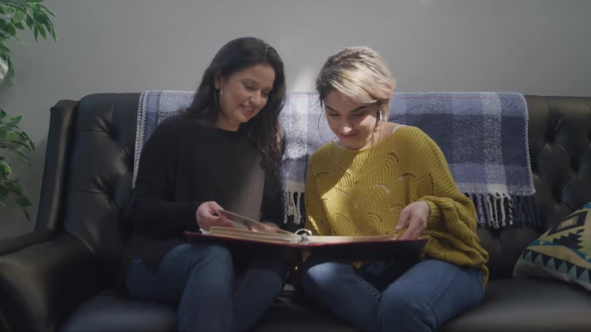 Two women laugh as they flip through a photo album