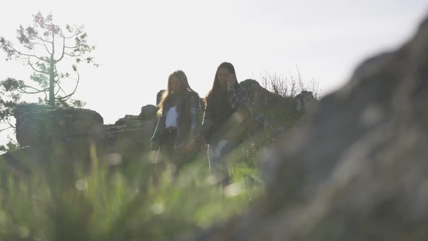 Two young woman descend down a path together while talking