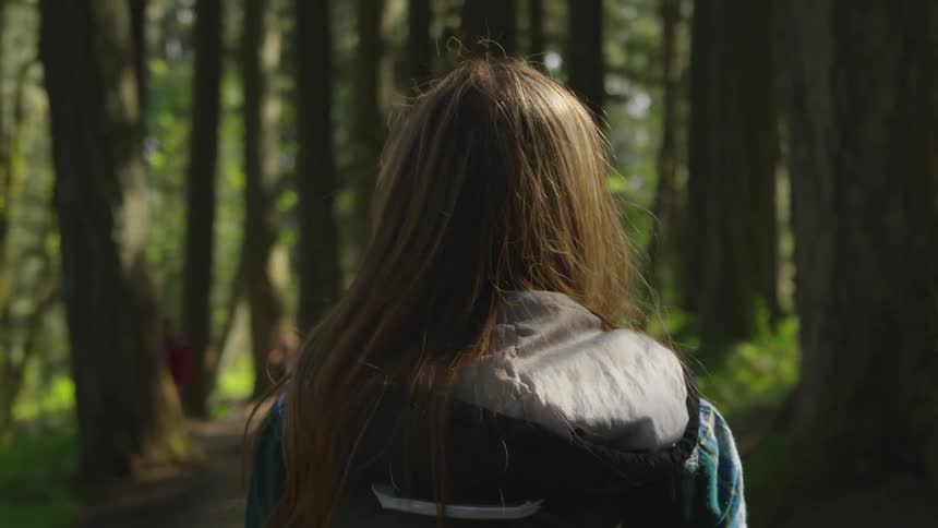 A girl is walking through a forest in spring