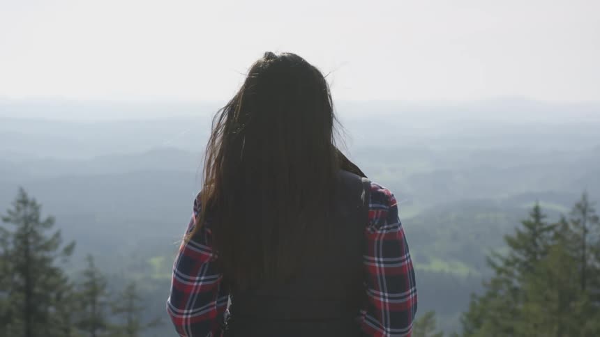 A woman is standing outdoors in a forest