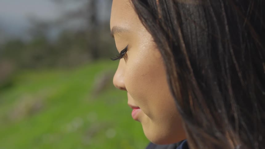 A woman is closing her eyes outdoors