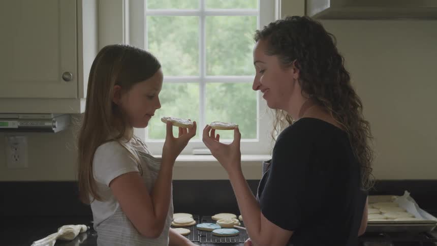 Mother an daughter try the iced cookies they have baked
