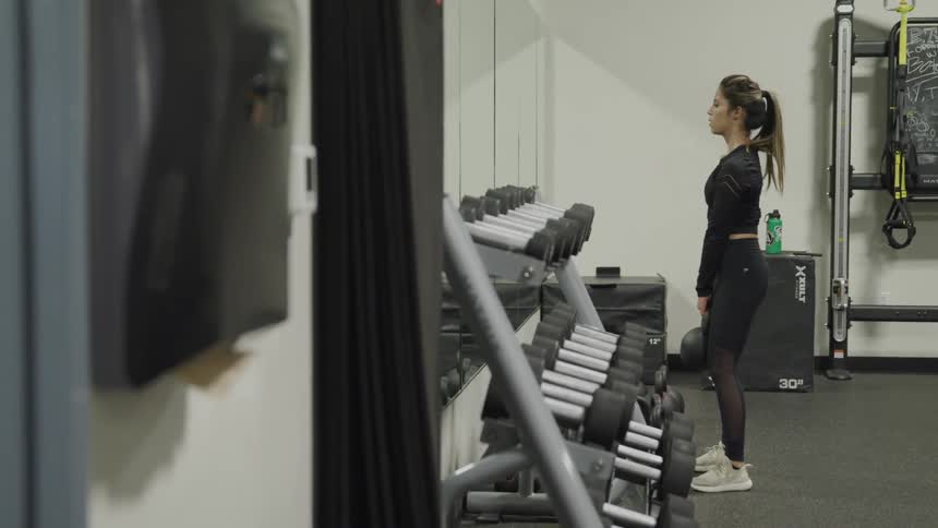 A teenage girl holds a kettle bell and squats