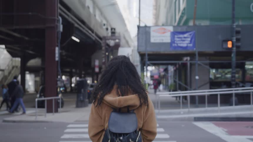 Pedestrians on a city street walking on the sidewalk and crossing at an intersection