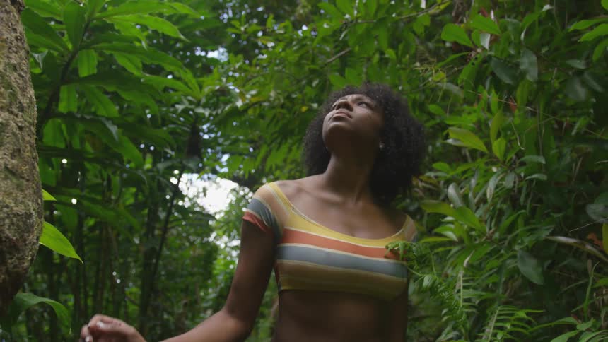 A woman is walking through a tropical area