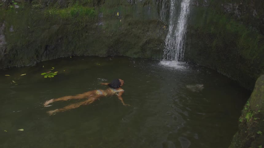 A teenage girl floats towards a waterfall