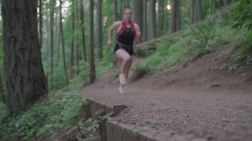 A woman is jogging through the forest