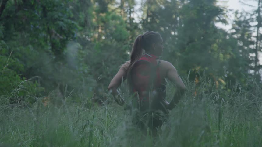 A teenage girl in a forest looks off in to the distance