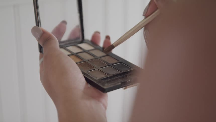 A woman is putting on makeup
