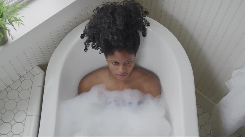 Young woman takes a bubble bath in the bathtub at home