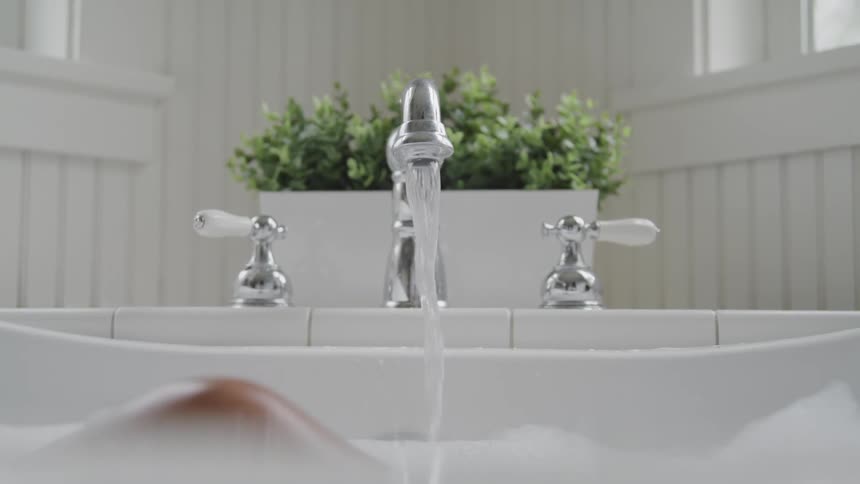 Water runs from faucet into bathtub with bubble bath