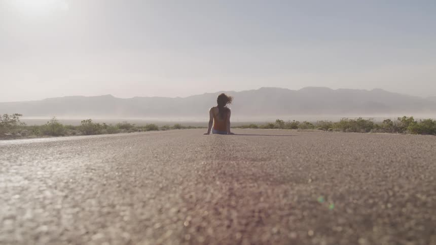 A woman sitting in the middle of a road