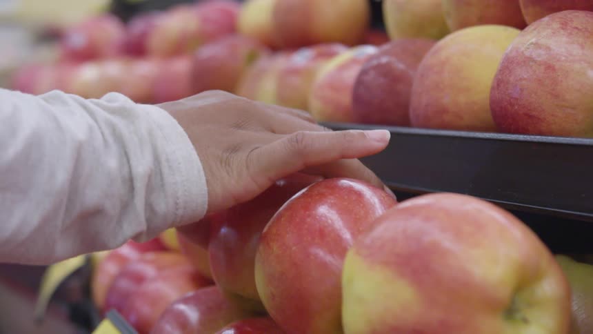 Picking an apple from fruit display at grocery store