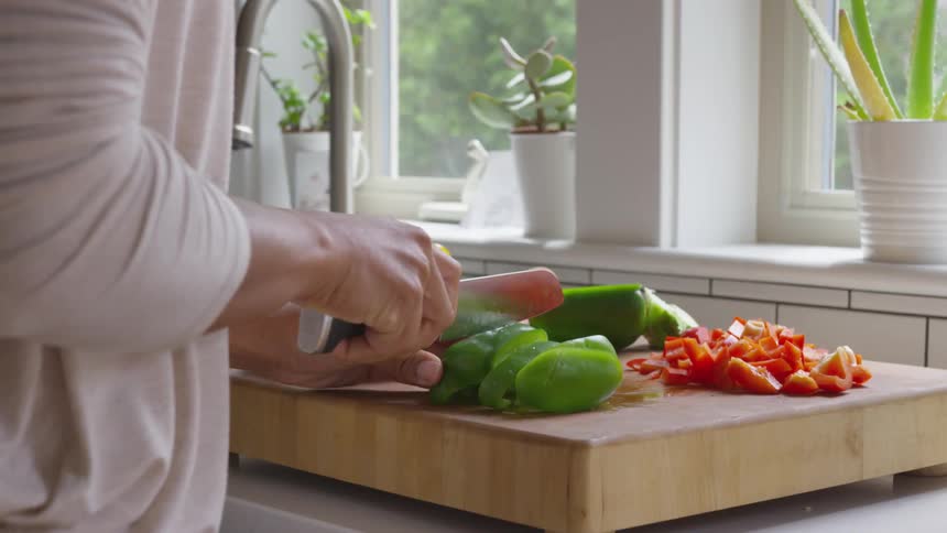A woman chops vegetables in her kitchen