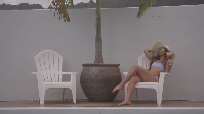 A woman with a bathing suit sitting on a chair next to a pool
