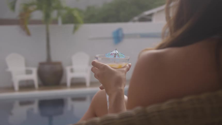 A woman has a drink poolside