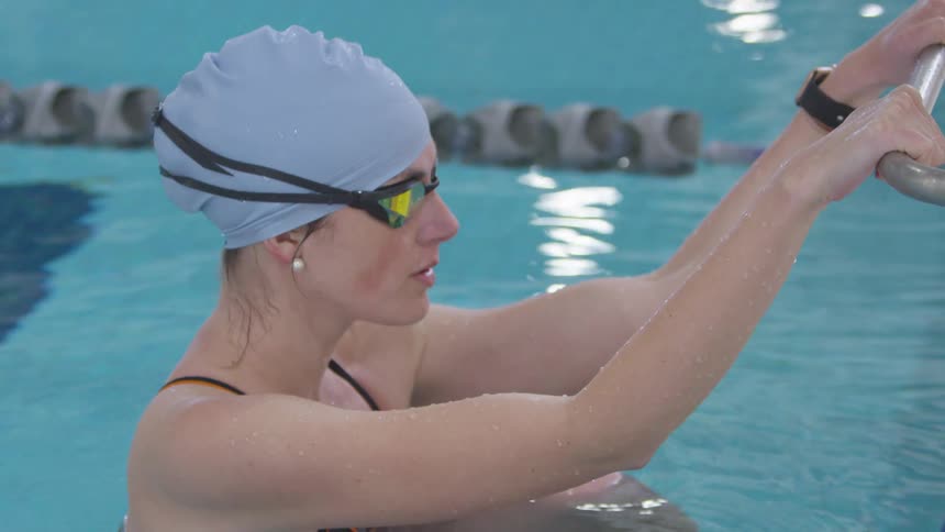 A woman with a bathing suit and goggles in a swimming pool with water