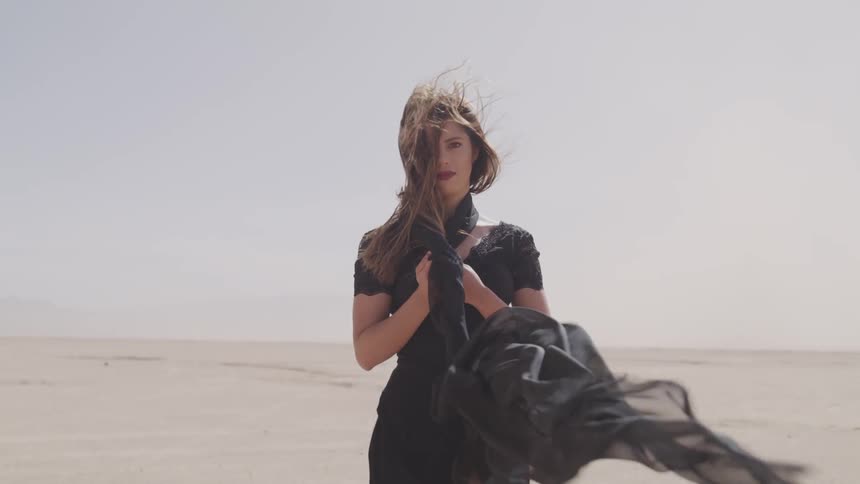 A teenage girl in a dress standing in the sand on a desert