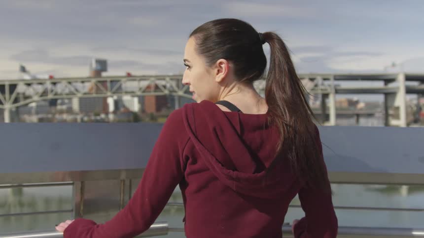 A woman stands on a balcony looking to the city river in front of her