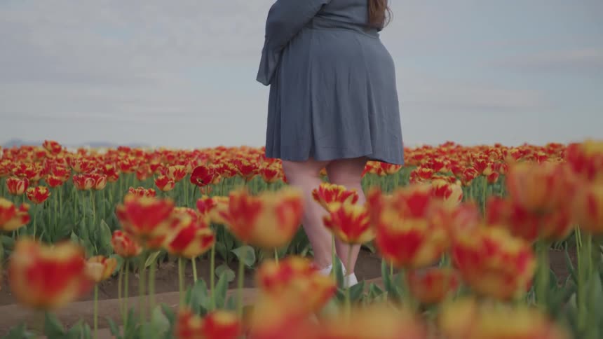 A woman is standing in a meadow of flowers