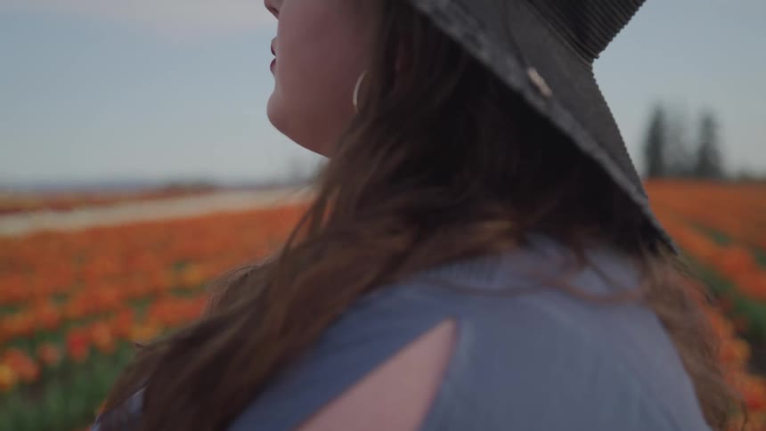 A woman is standing outdoors by a meadow