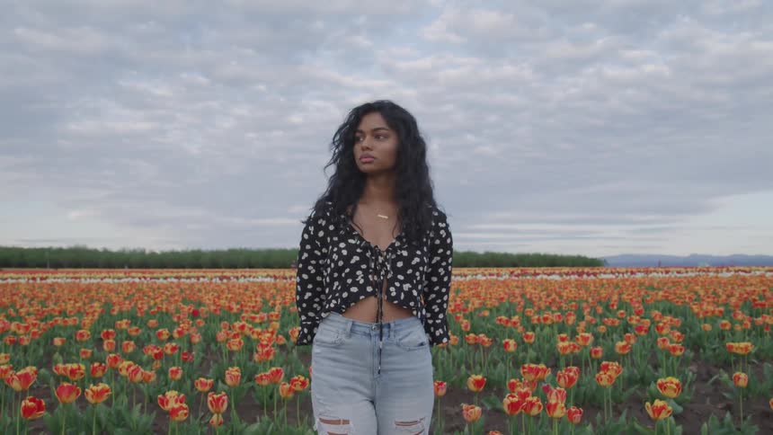 A woman is standing in a field full of flowers