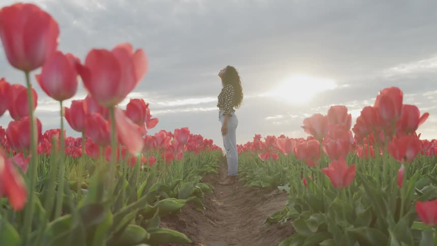 Young woman stands in tulip field looking toward ssky