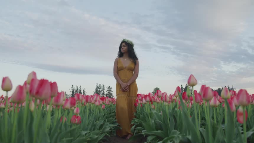 A woman is standing in a field of flowers