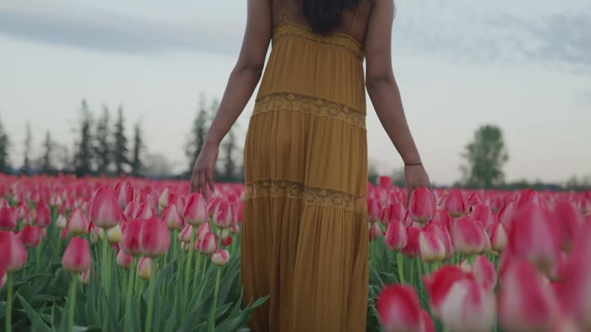 A woman walking through a field of flowers