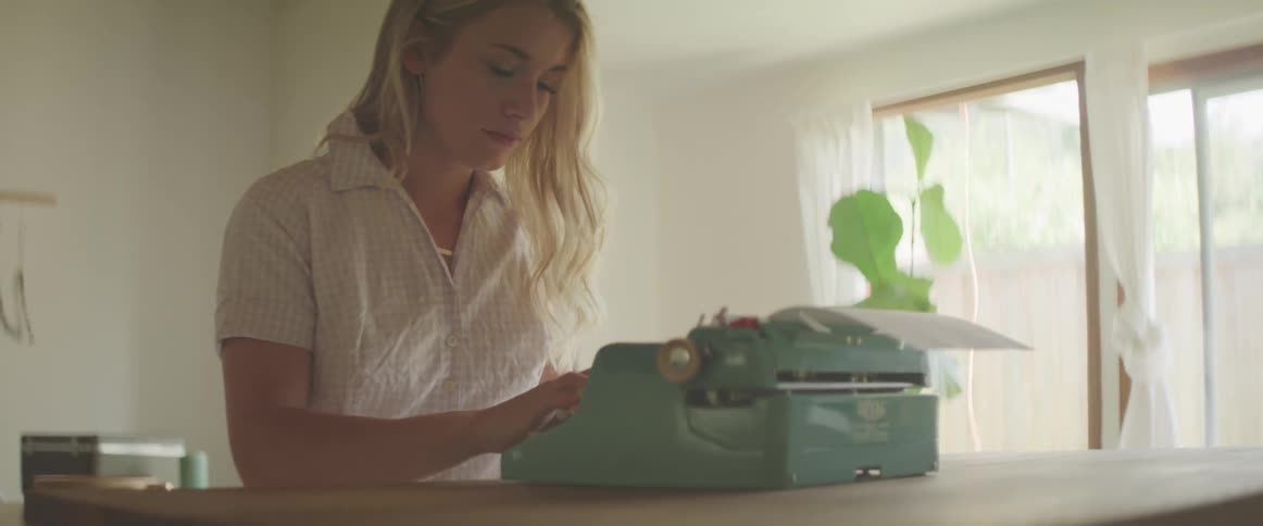 A teenage girl typing on a vintage typewriter at home