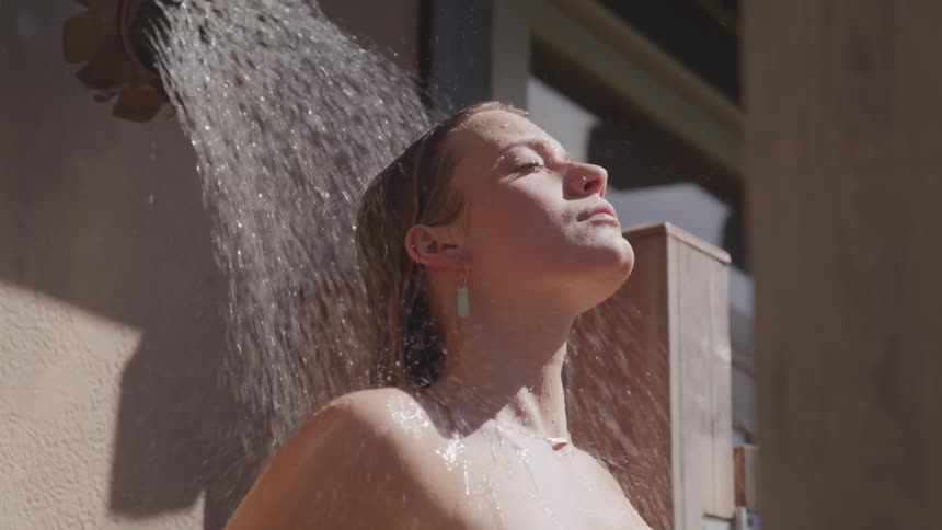 A woman is taking a shower outdoors