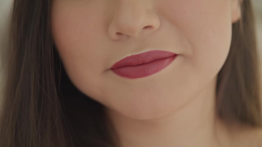 Woman wearing lipstick smiles slightly