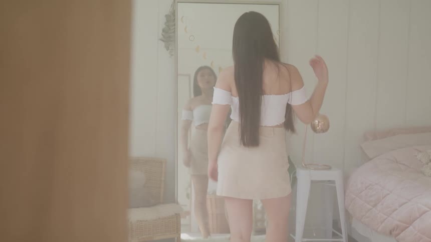 A female standing in front of a mirror posing