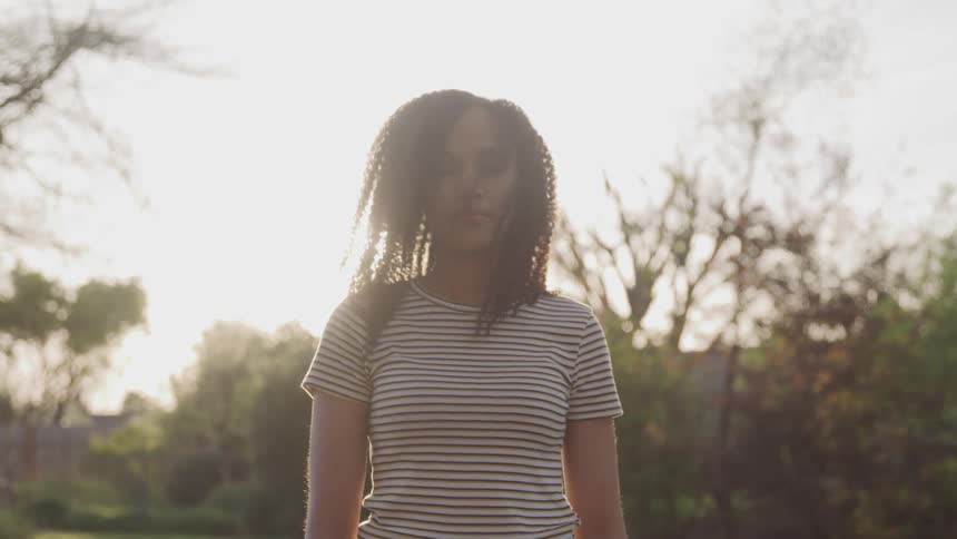 A woman is standing outdoors at dusk