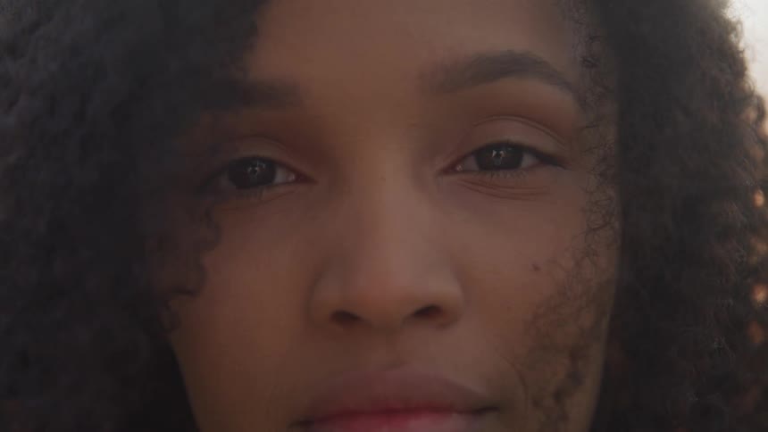 Black woman with curly hair stares at the camera