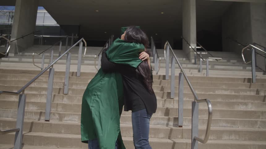 A woman hugs a person in a cap and gown