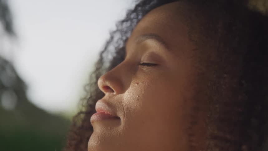 Woman closes her eyes to bask in sunlight