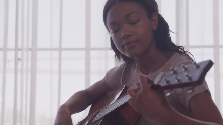A female strumming on a guitar