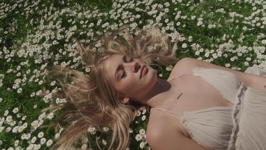 A woman is laying down on a field of flowers