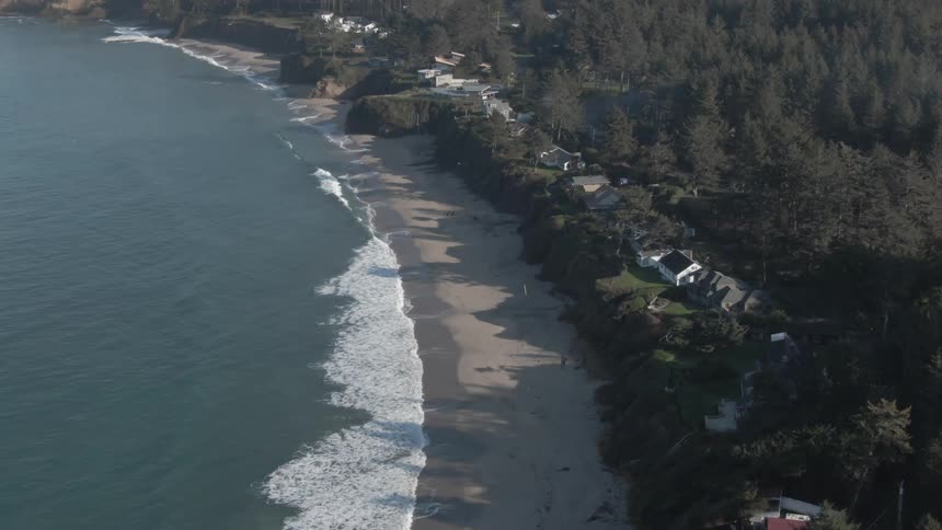 Ocean waves wash into a small beach bordering a neighborhood